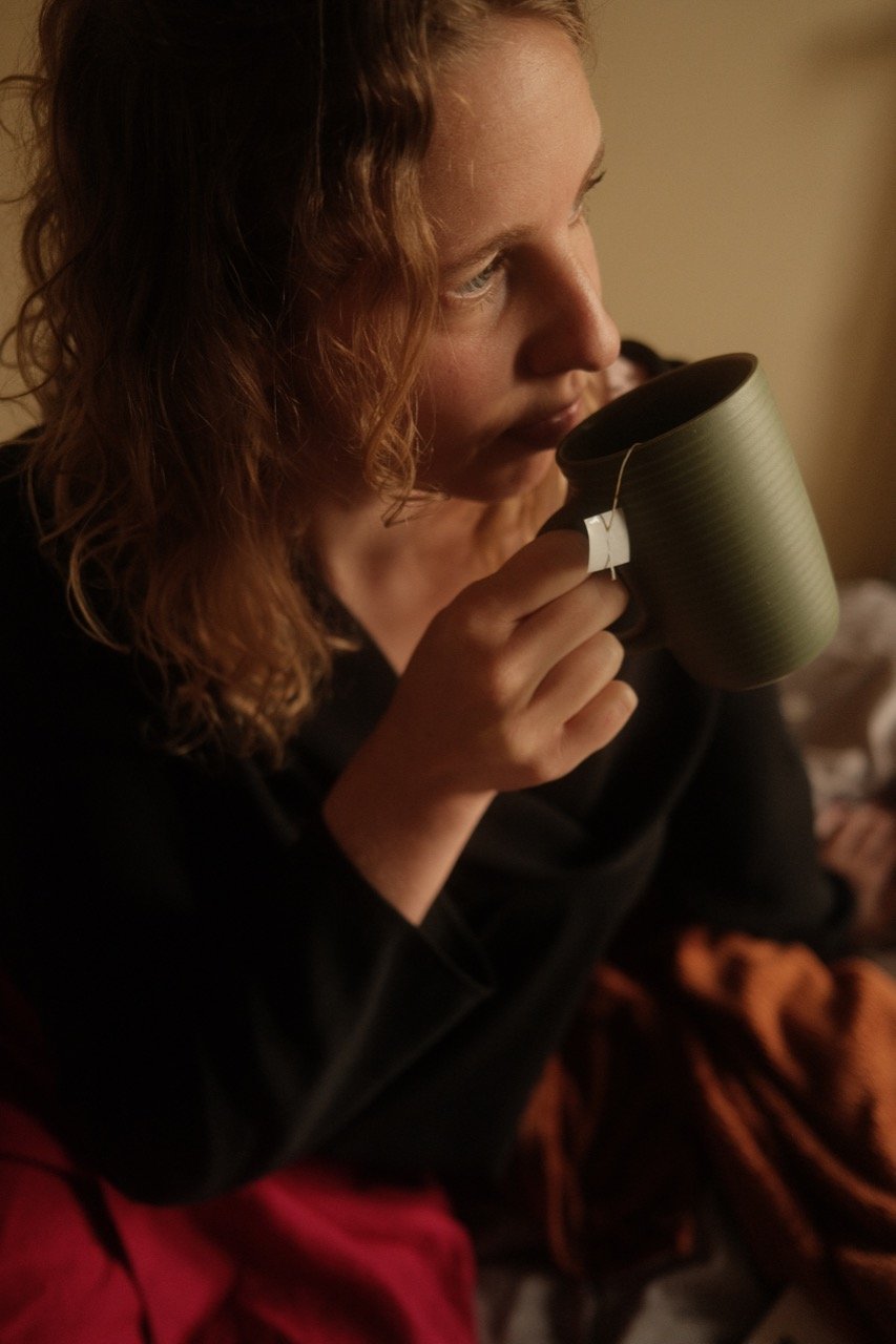 Flora holding a mug close to her face.
